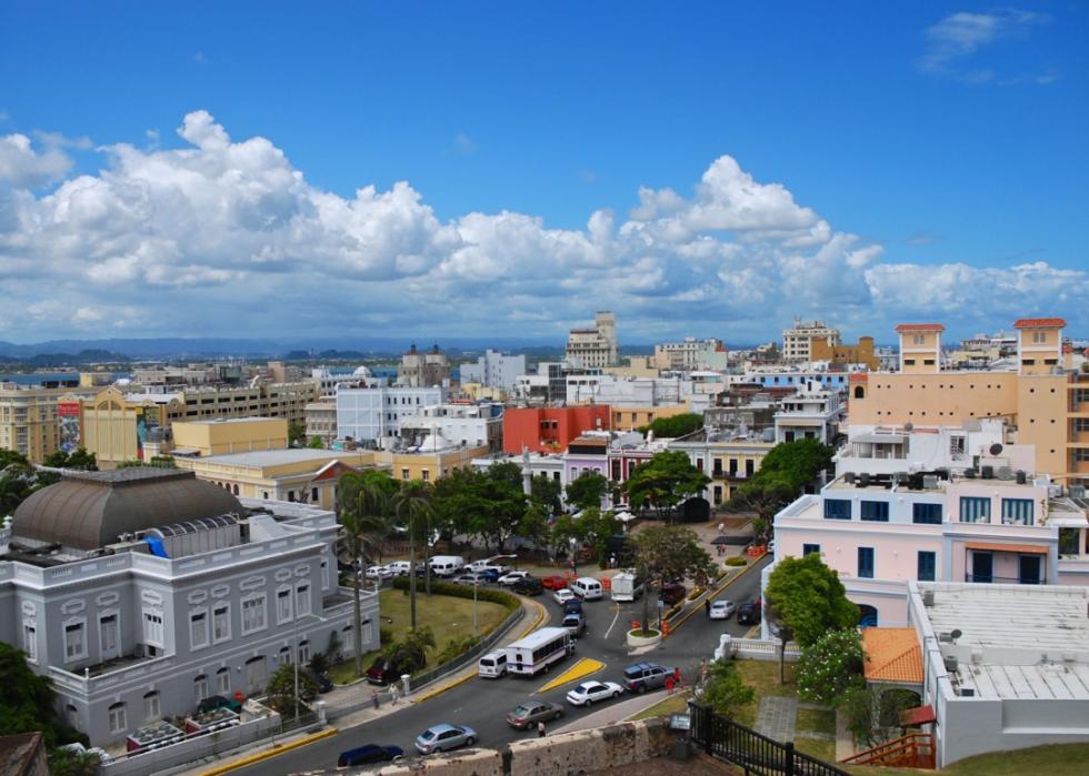 Colorful modern and historic buildings with pastel hues line the streets with traffic.