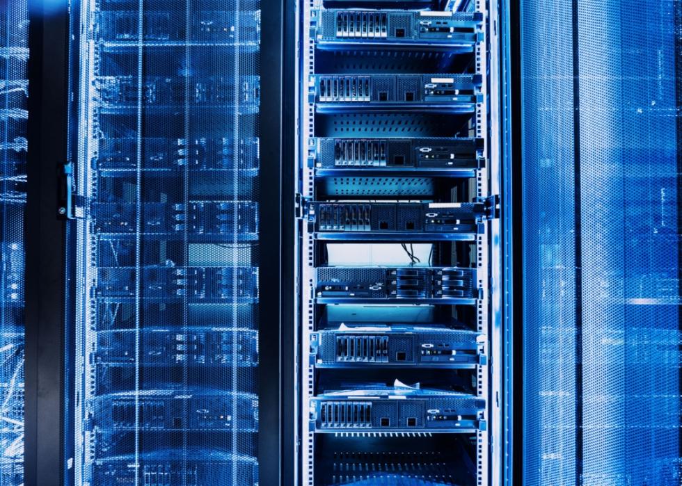 Multiple racks filled with hardware devices in a blue lit room.