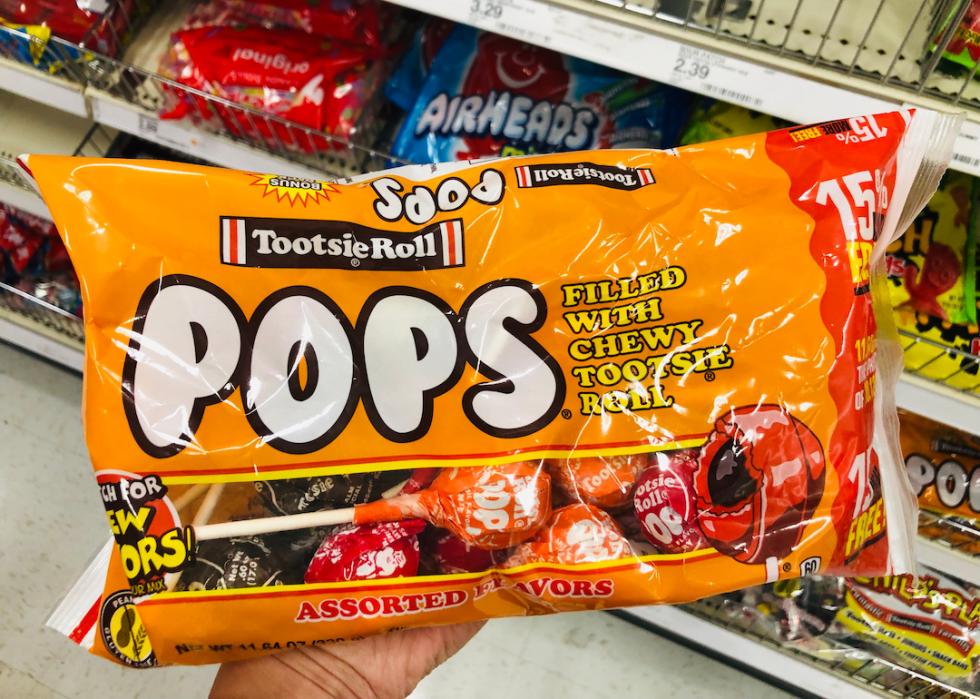 Hand holds up a package of Tootsie Pops.