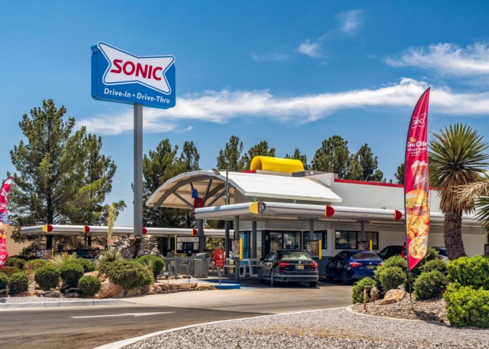 The exterior of a Sonic restaurant with a free standing sign displaying the Sonic logo.