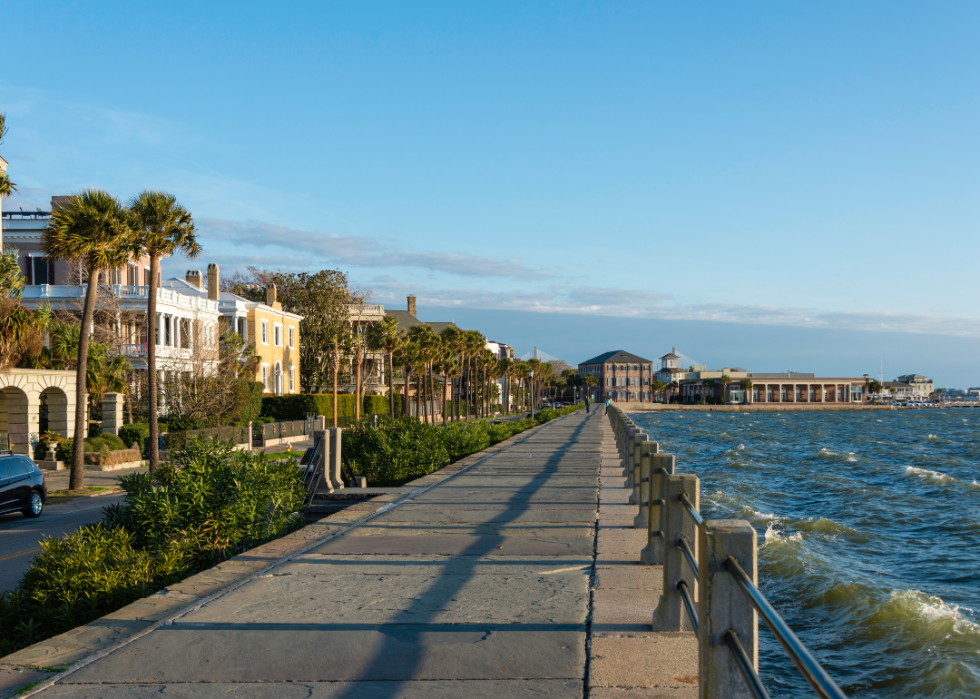 Buildings and palm trees along the promenade by the body of water.