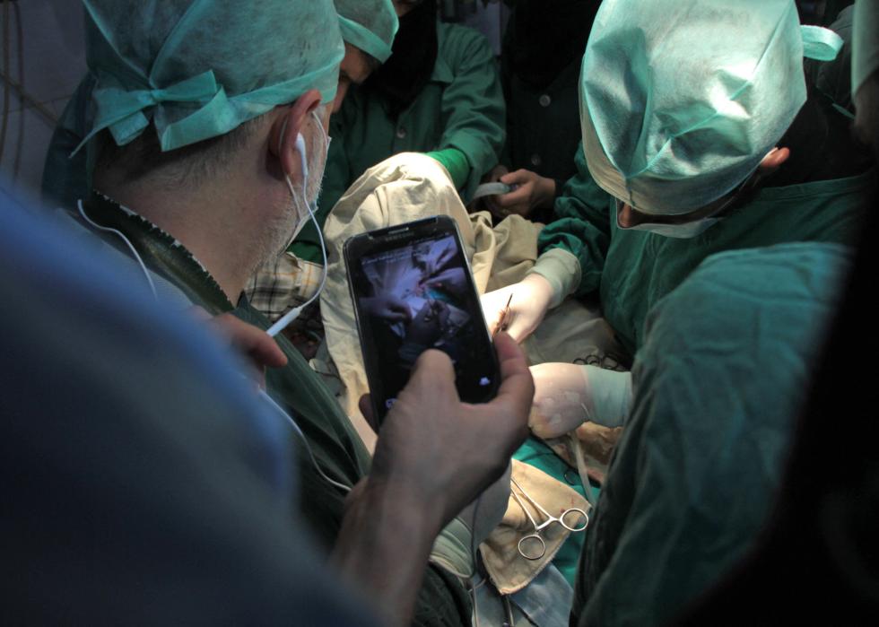 A surgeon holds his phone up during surgery.