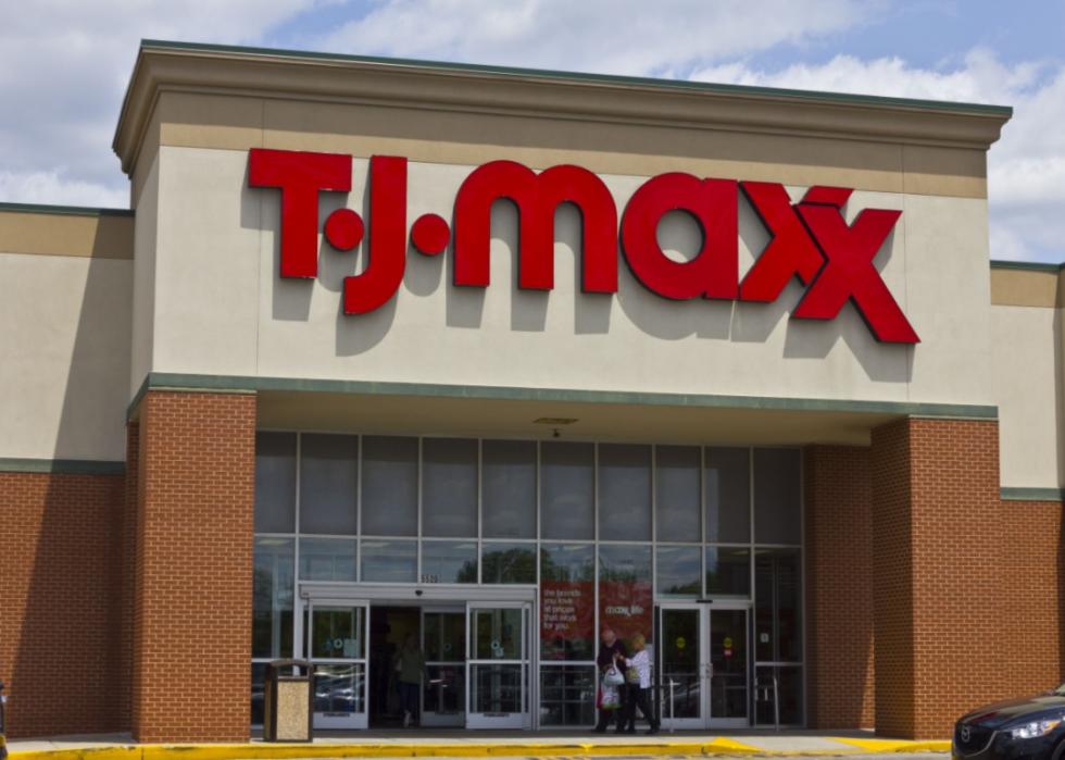 The front of a TJ Maxx store with two people walking out with bags in their hands.