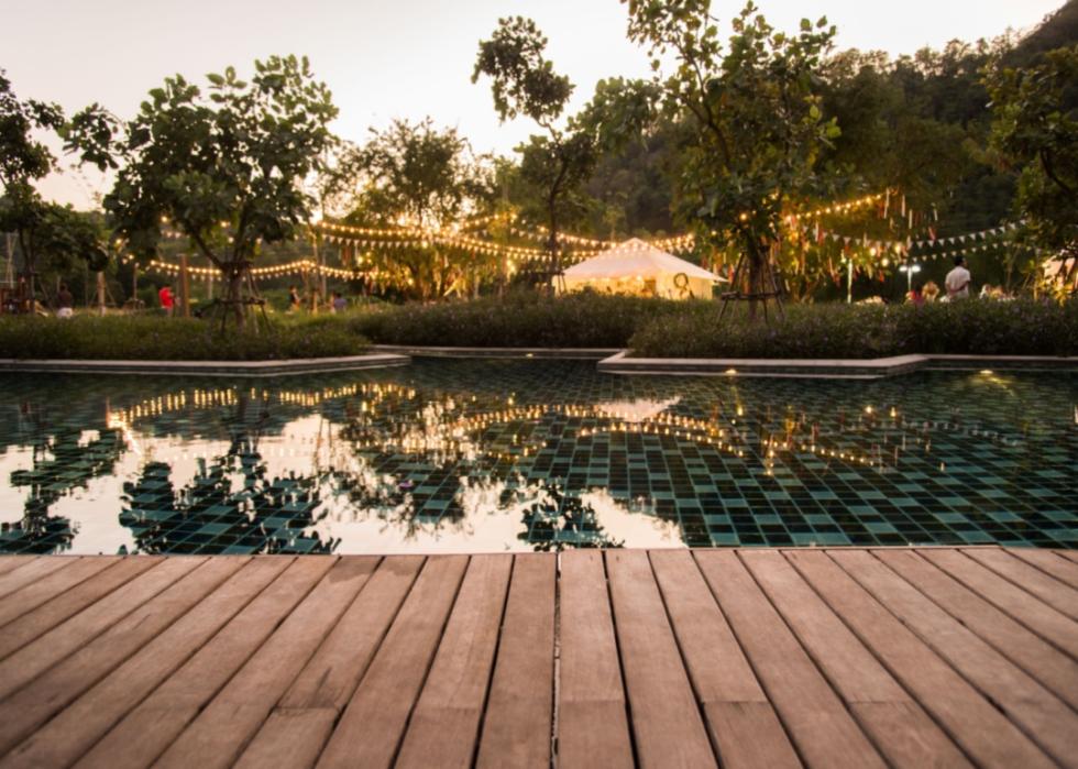 A backyard party set up near a pool with a tent and lights.