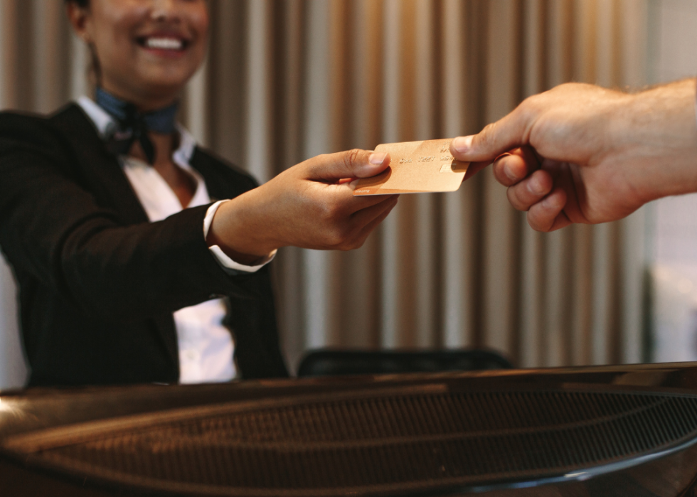 A hotel concierge handing a credit card to a guest.