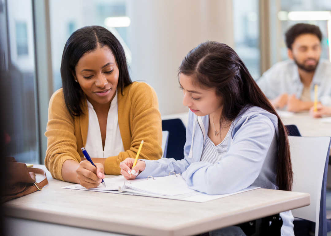 Two young women work together in a classroom setting.