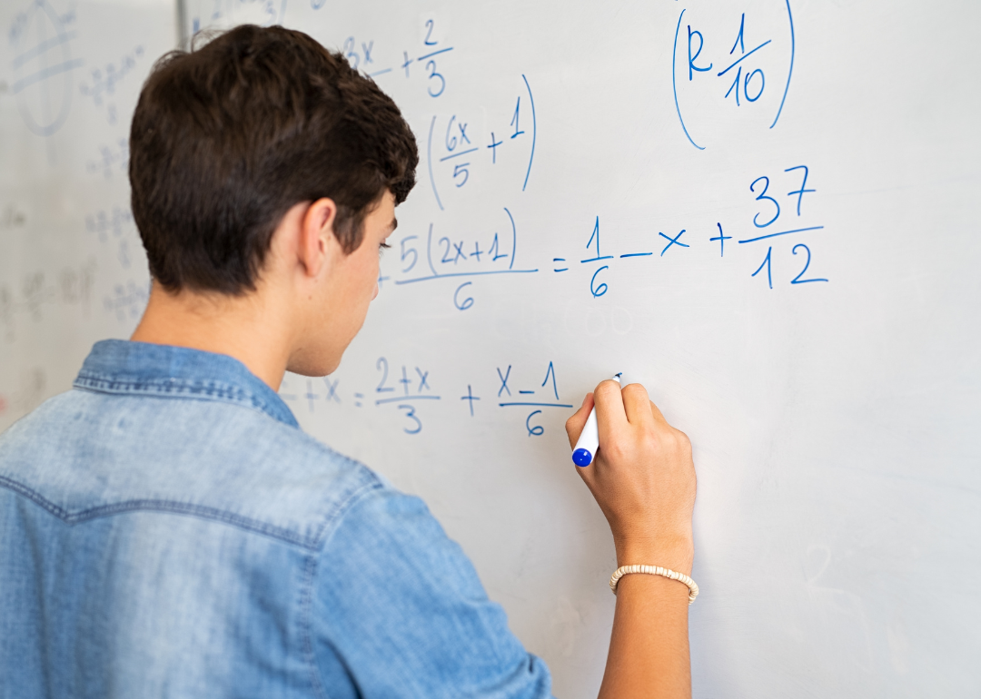 A student solving a math equation on a whiteboard.