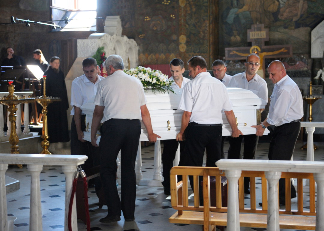Attendants move a casket in a church.