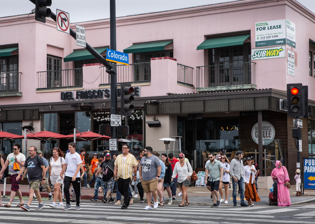 A crowd of people walking across the street at Ocean and Colorado Avenue near the Santa Monica Pier on June 12, 2022, in Santa Monica, California.