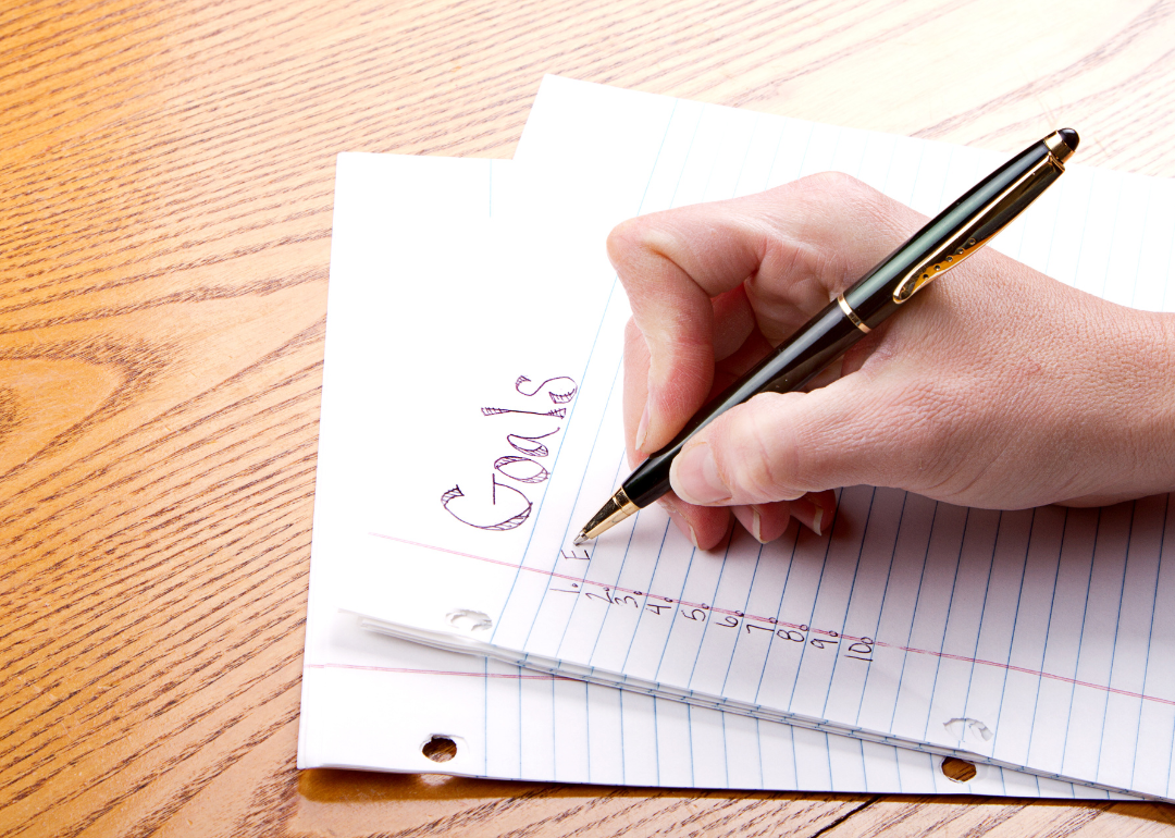 A person's hand writing down a list of goals.