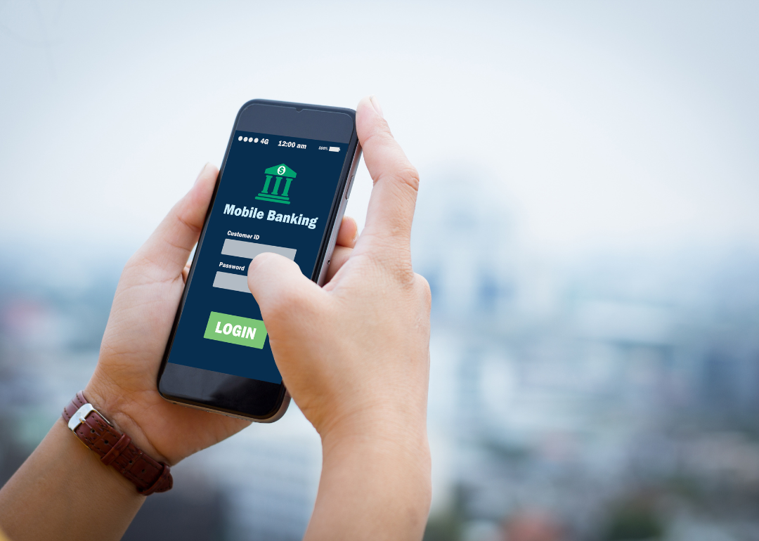 A person holding a phone that is open to a mobile banking app.