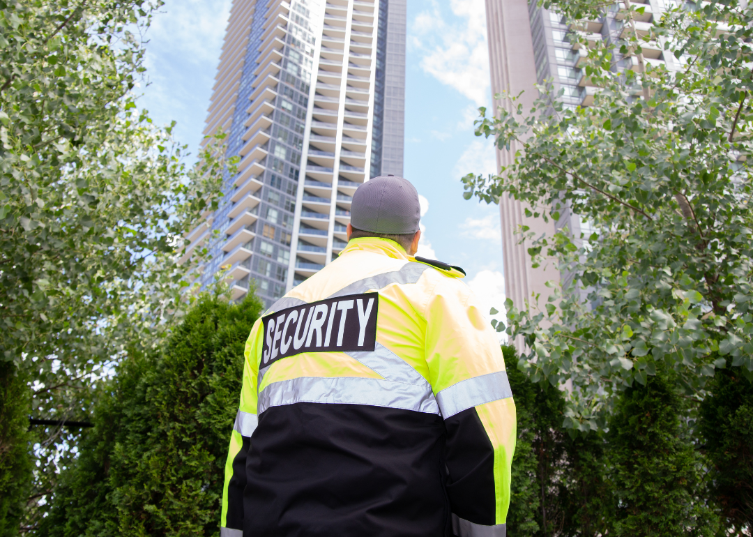 A security guard outside a tall building.
