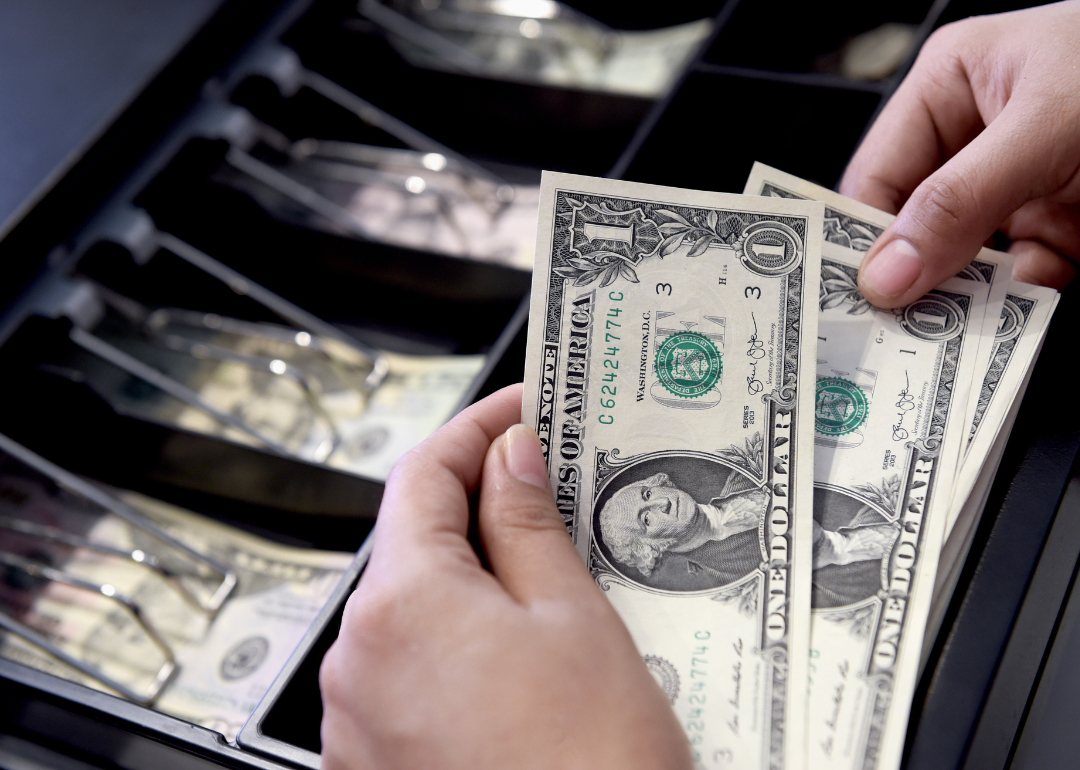 A cashier putting money in their register.