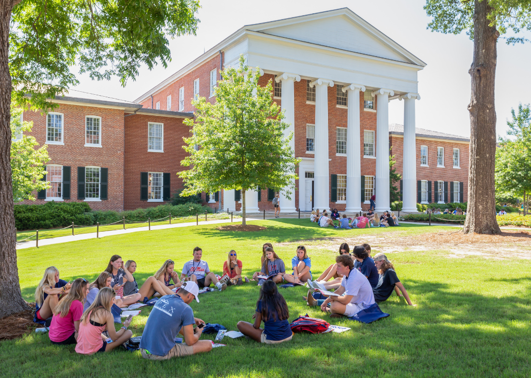 A group of students sitting in the grass on the campus of the University of Mississippi.