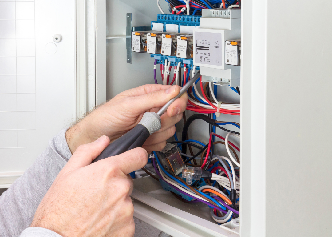 An electrician working on an electrical panel