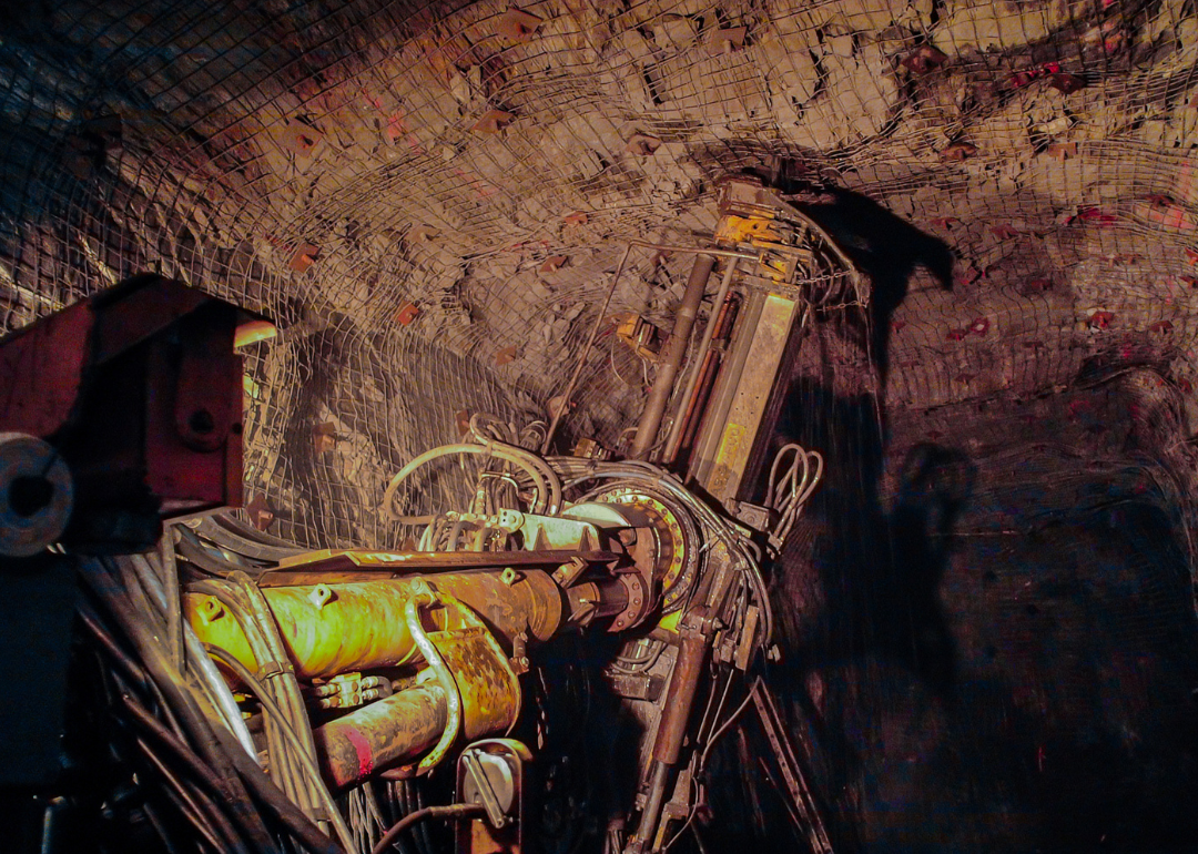 A heavy machine attaches large bolts the ceiling of a mine.