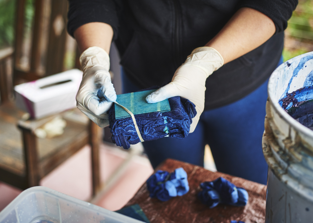 A worker dyes some fabric blue.