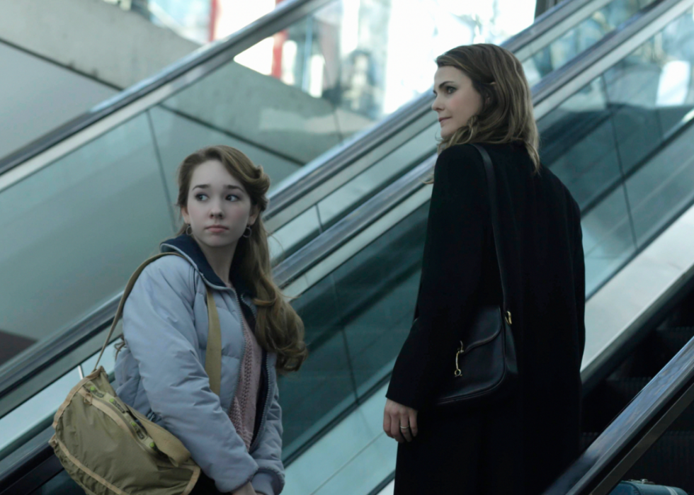 Elizabeth Jennings (Keri Russell) and Paige Jennings (Holly Taylor) looking backwards at an airport