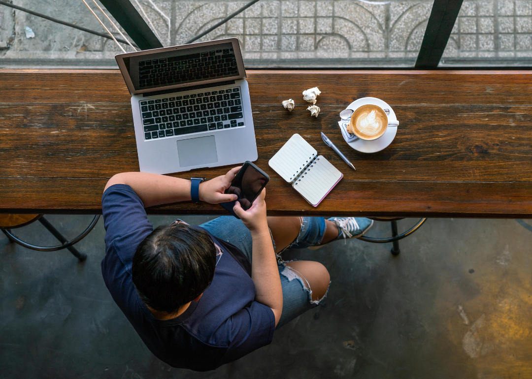A remote worker with a mug of coffee on their laptop at a coffee shop 