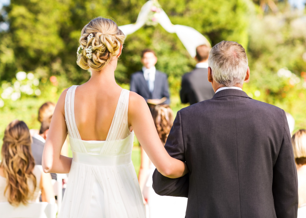 A bride and her father walking down the aisle during an outdoor wedding