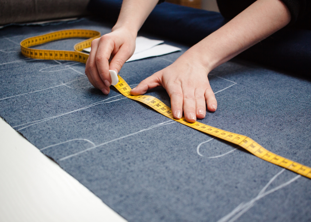 An apparel patternmaker measures some fabric.