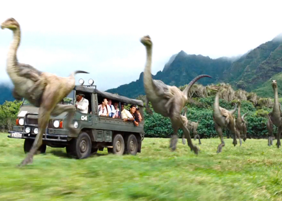 Dinosaurs running around a car in Jurassic World