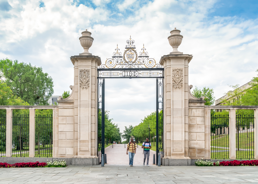 Two people walking through the campus gates of the University of Arkansas.