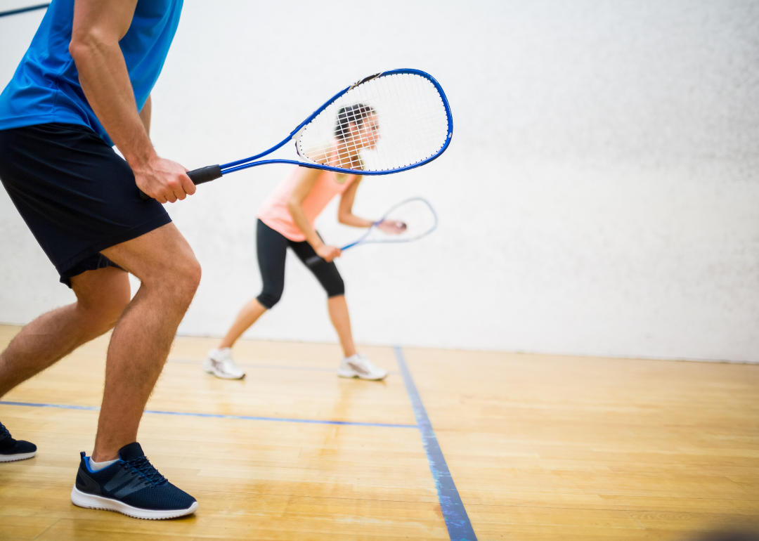 A woman about to serve the ball in a squash court