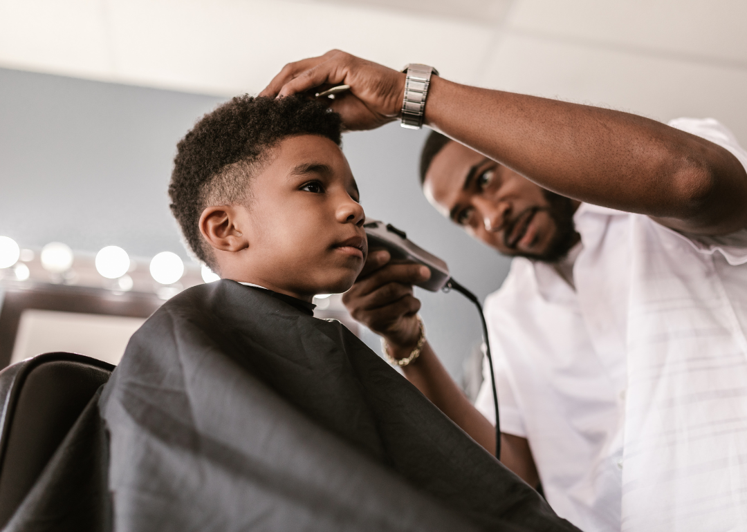 A barber trims the hair of a young boy.