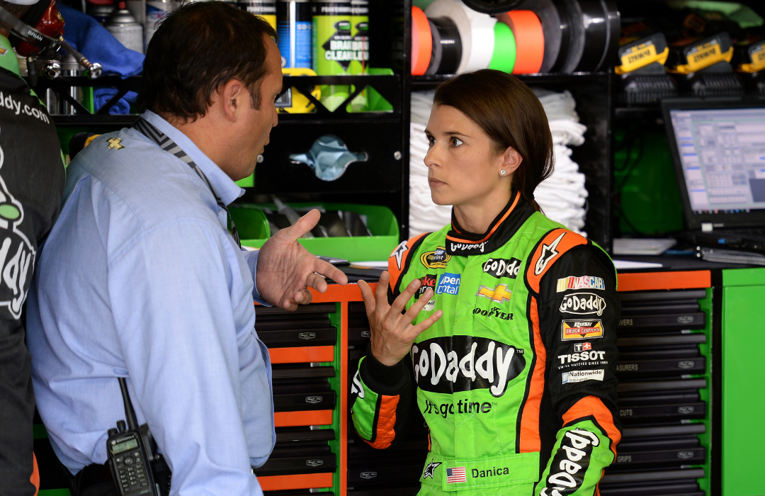 Danica Patrick, driver of the #10 GoDaddy Chevrolet, talking with Greg Zipadelli, director of competition at Stewart-Haas Racing, in a garage area during practice for the NASCAR Sprint Cup Series Quicken Loans 400.