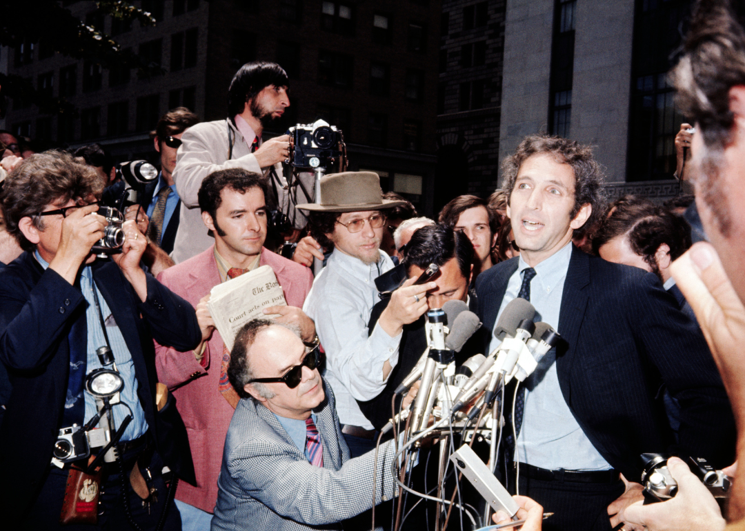 Daniel Ellsberg appearing before microphones, surrounded by reporters at the Federal Building.