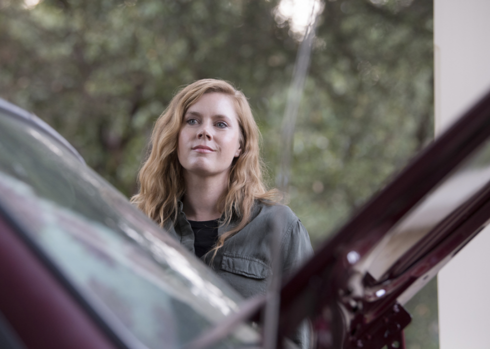 Camille Preaker (Amy Adams) standing outside a car with a small smile