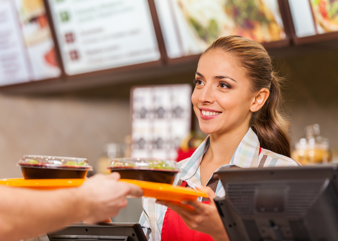 A woman hands fast food to a customer.