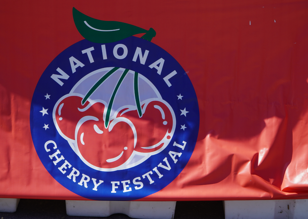 A sign with the logo for the National Cherry Festival hanging over a barricade.