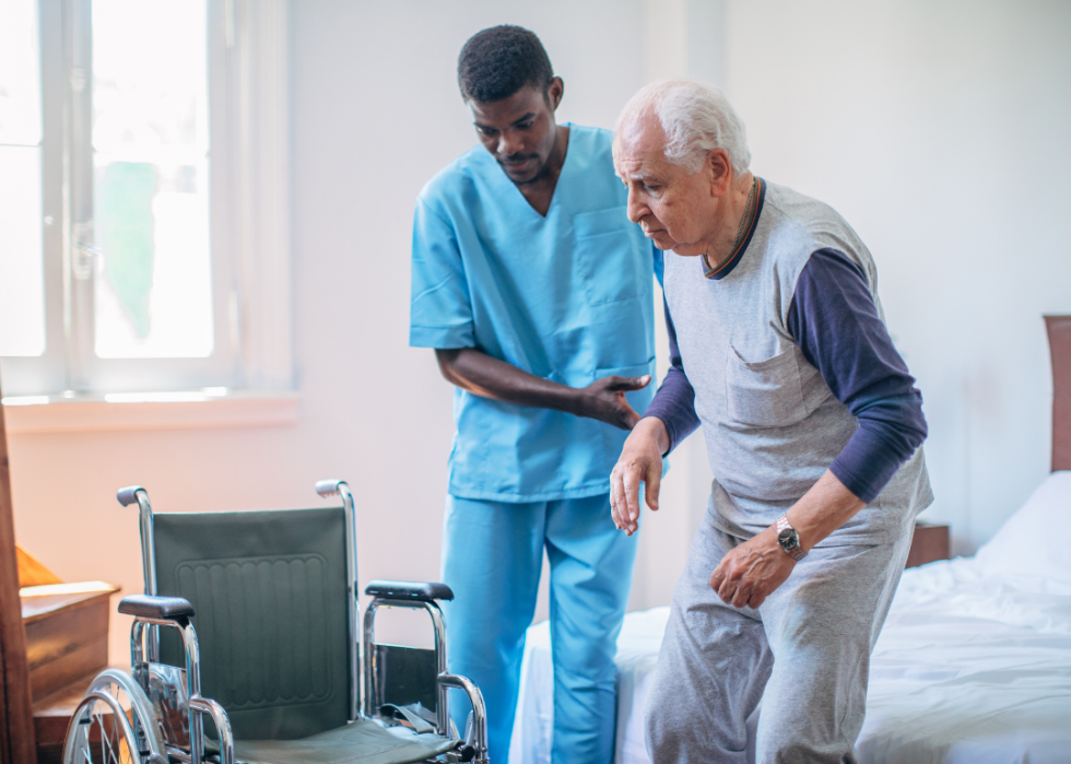 A nurse practitioner helping a senior man into his wheelchair