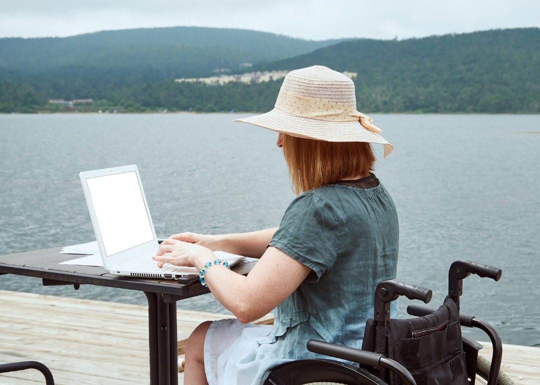 A person in a wheelchair working remotely at a lake 