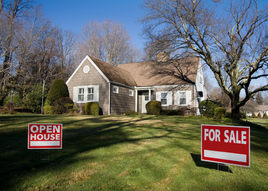 A home with 'Open House' and 'For Sale' signs in front of it