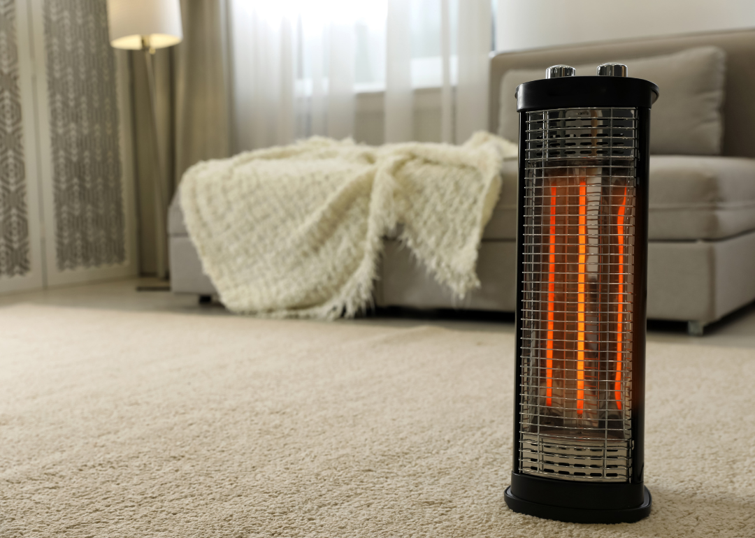 A modern electric halogen heater on the carpeted floor of a living room.