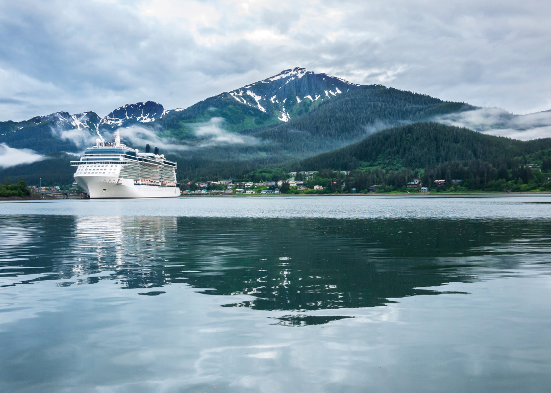 A cruise ship at a port in Juneau with a snow capped mountain and low-lying fog in the background.