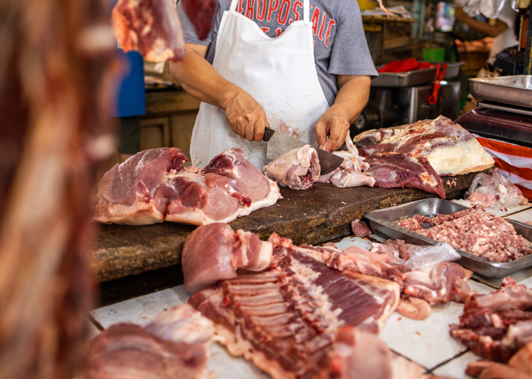 A worker cuts meat.