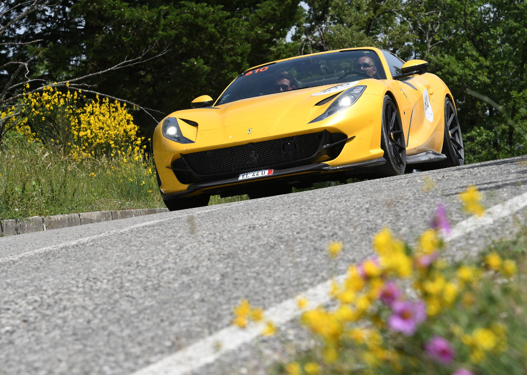 A Ferrari 812 GTS driving down a road in Italy during a parade.