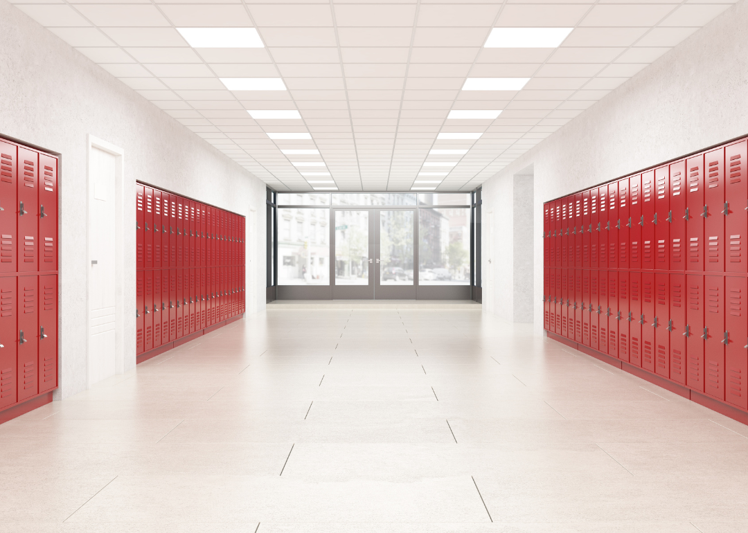 An empty school hallway lined with red lockers.