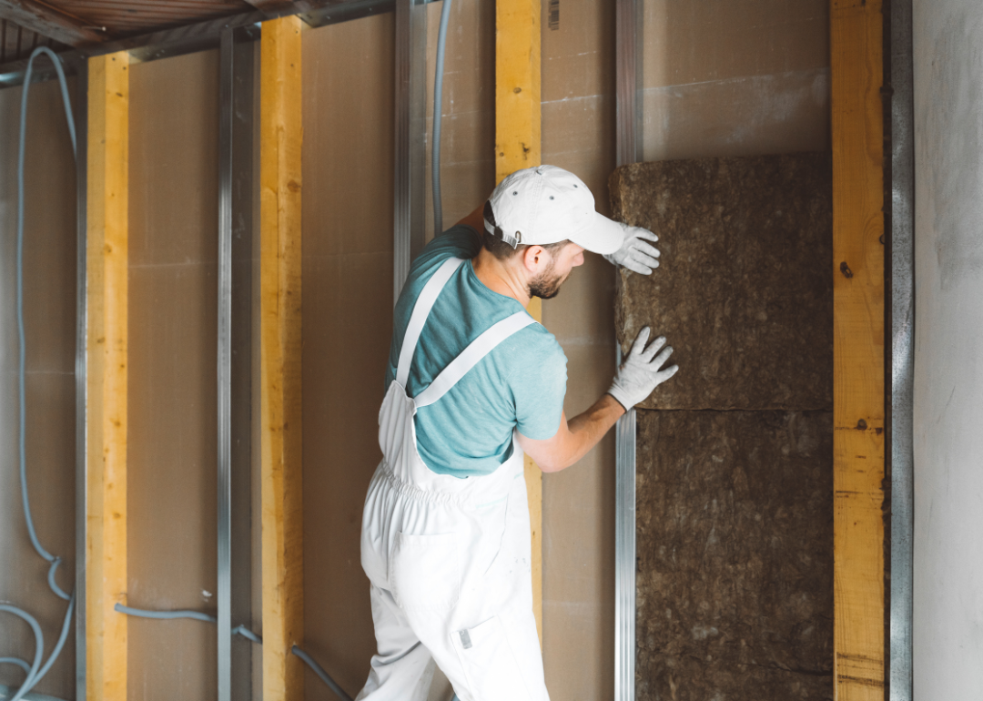 A worker insulating a home's walls during a renovation project