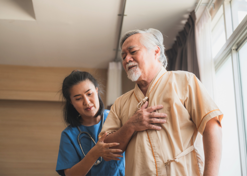 Older male patient being cared by woman nurse while experiencing chest pains.