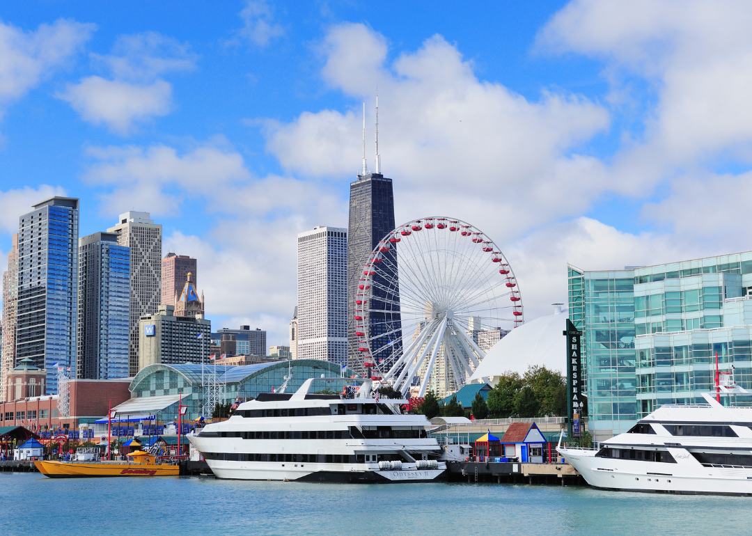 The Chicago skyline with a Ferris wheel and yachts on the water.