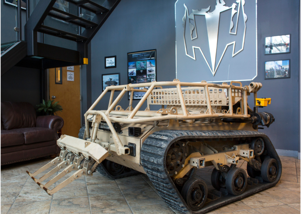 A relatively small military tank robot on display in a building.