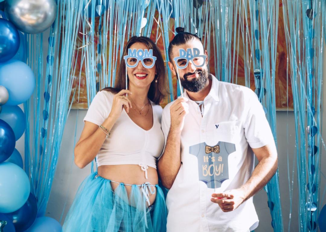 A mom and dad posing with baby boy props for a photo booth.