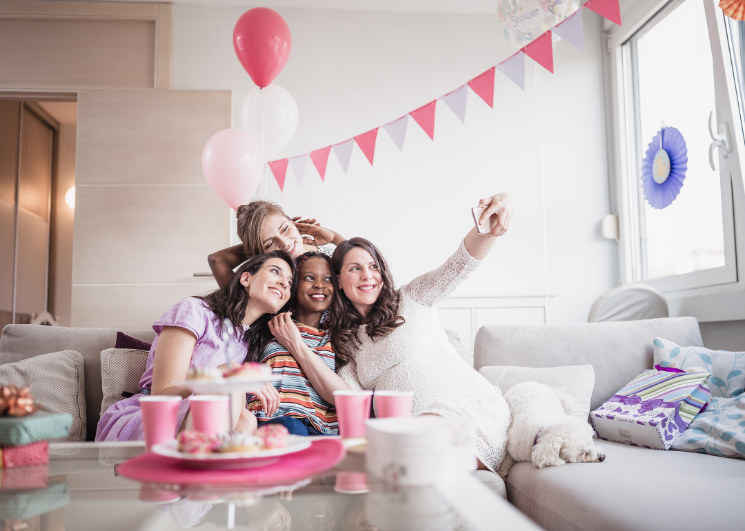 Women sitting on a couch taking a selfie.