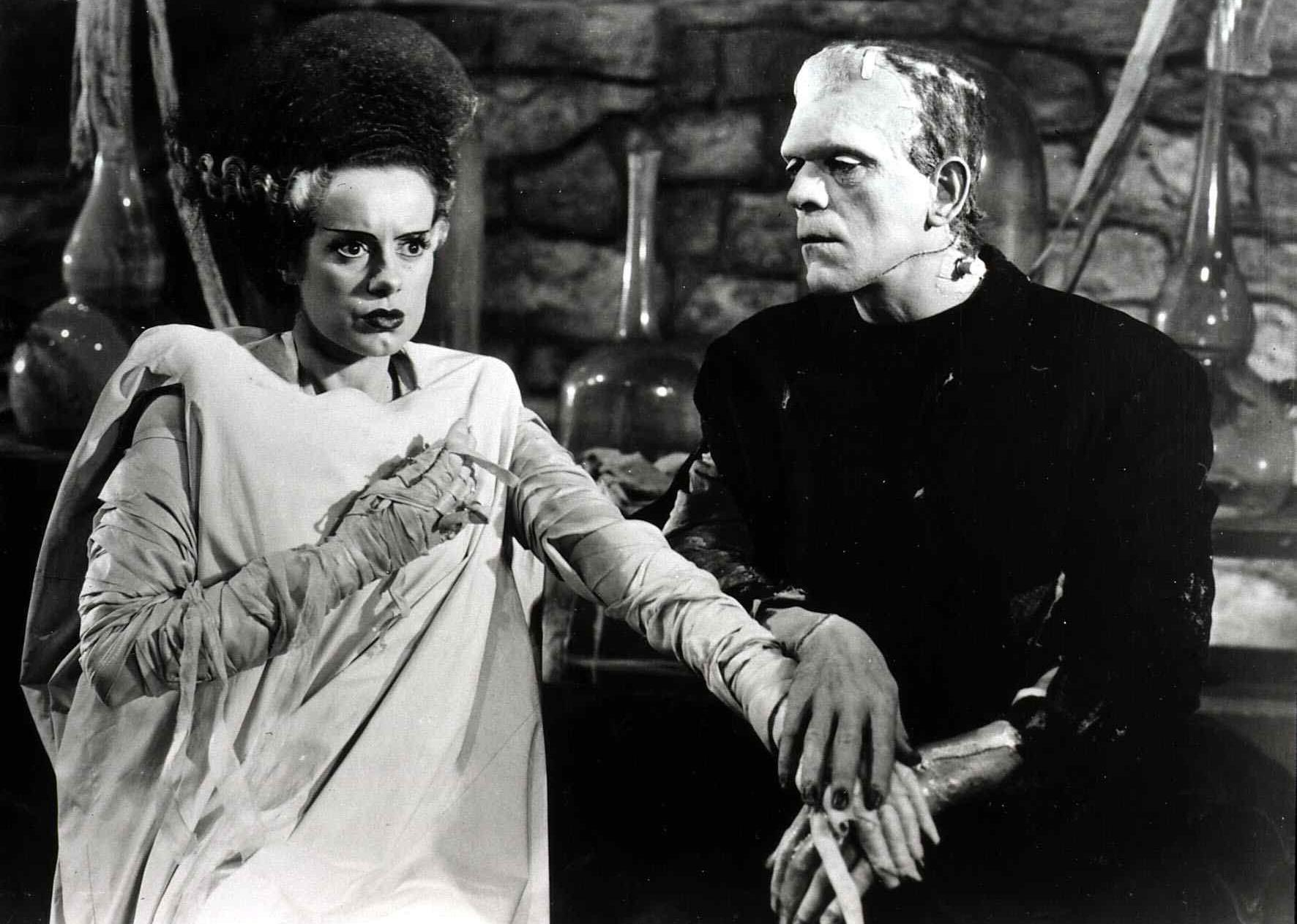 Frankenstein and his bride hold hands.