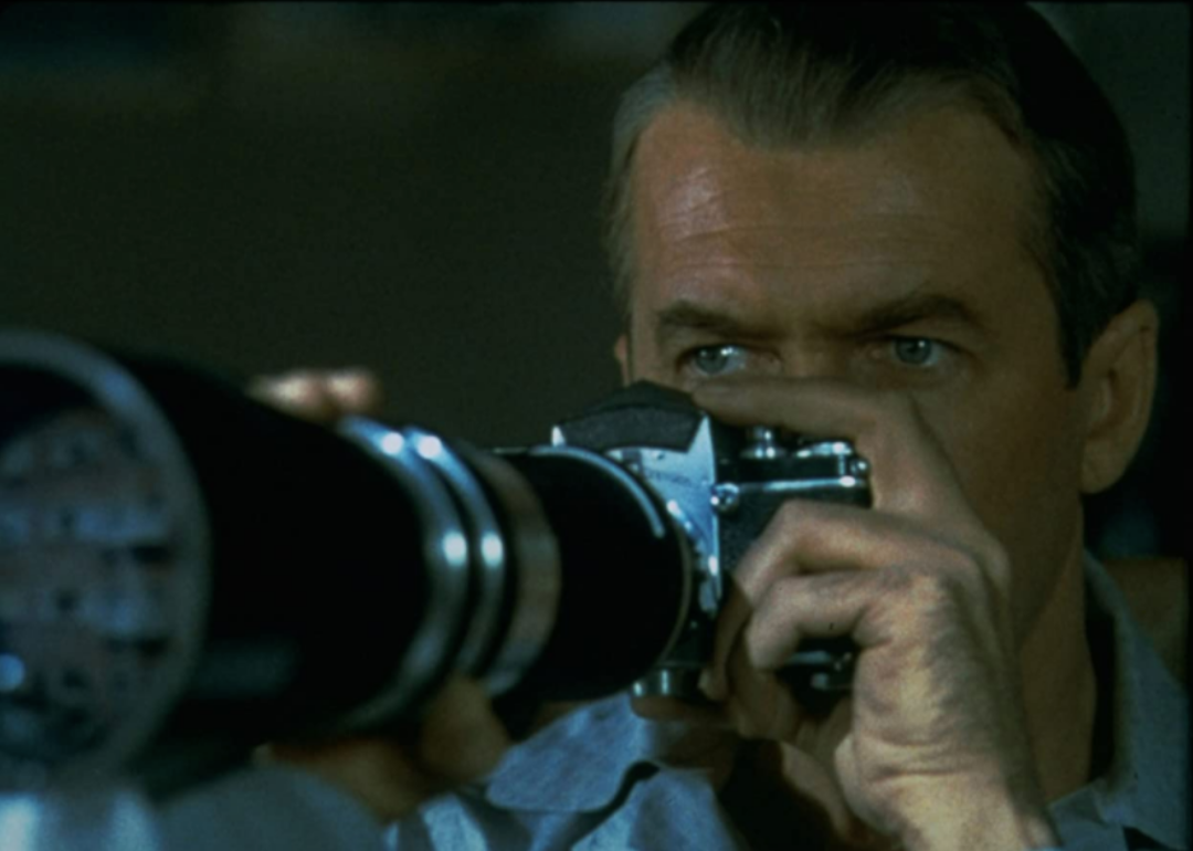 James Stewart looking through a large photo lens.